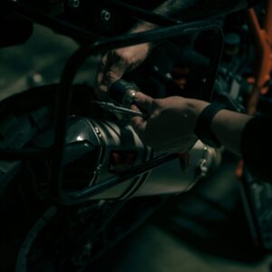 Hands working under the hood of an engine.