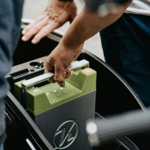 Hands reaching for a car battery.