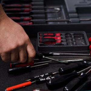 A hand picks up tools from a bench.