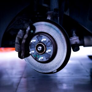 A vehicle's brake and rotors are exposed in a workshop.